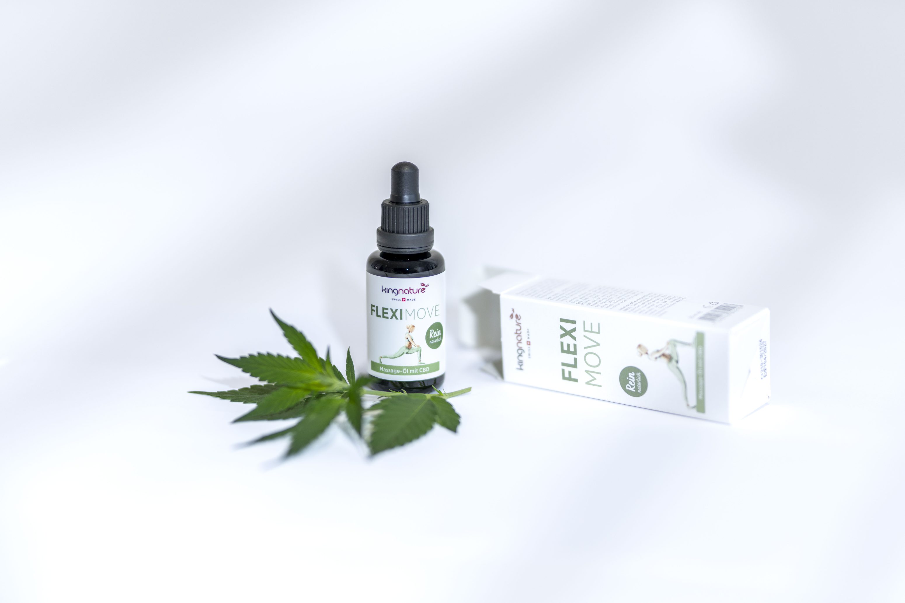 Eine Tropfflasche mit der Aufschrift FLEXI MOVE steht neben der Verpackung und zwei grünen Cannabisblättern auf einer weißen Fläche. Auf der Verpackung ist eine Person abgebildet, die sich dehnt, was auf ein Gesundheits- oder Wellnessprodukt hindeutet.