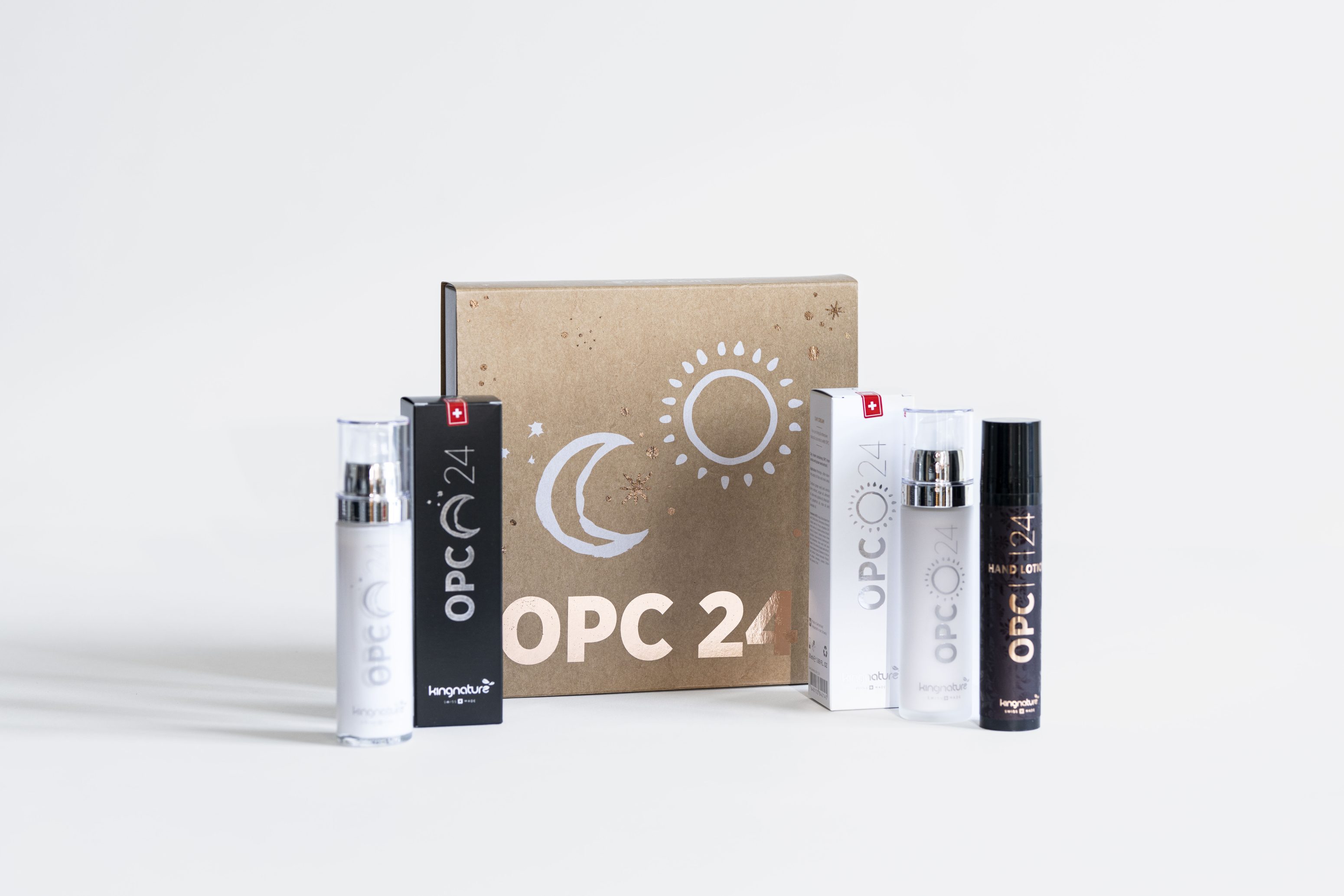 Eine Reihe von OPC 24 Hautpflegeprodukten, einschließlich Flaschen und Schachteln, sind vor einer braunen Schachtel mit Mond- und Sonnengrafiken auf weißem Hintergrund angeordnet.