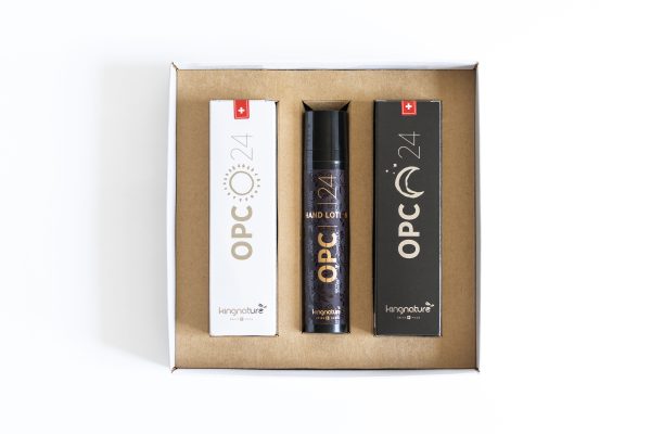 Eine Pappschachtel, die drei Produkte enthält: zwei rechteckige Schachteln mit der Aufschrift "OPC 24" auf der linken und rechten Seite und eine Flasche in der Mitte mit der Aufschrift "OPC 24 Hand Lotion" von kingnature, alles auf weißem Hintergrund.