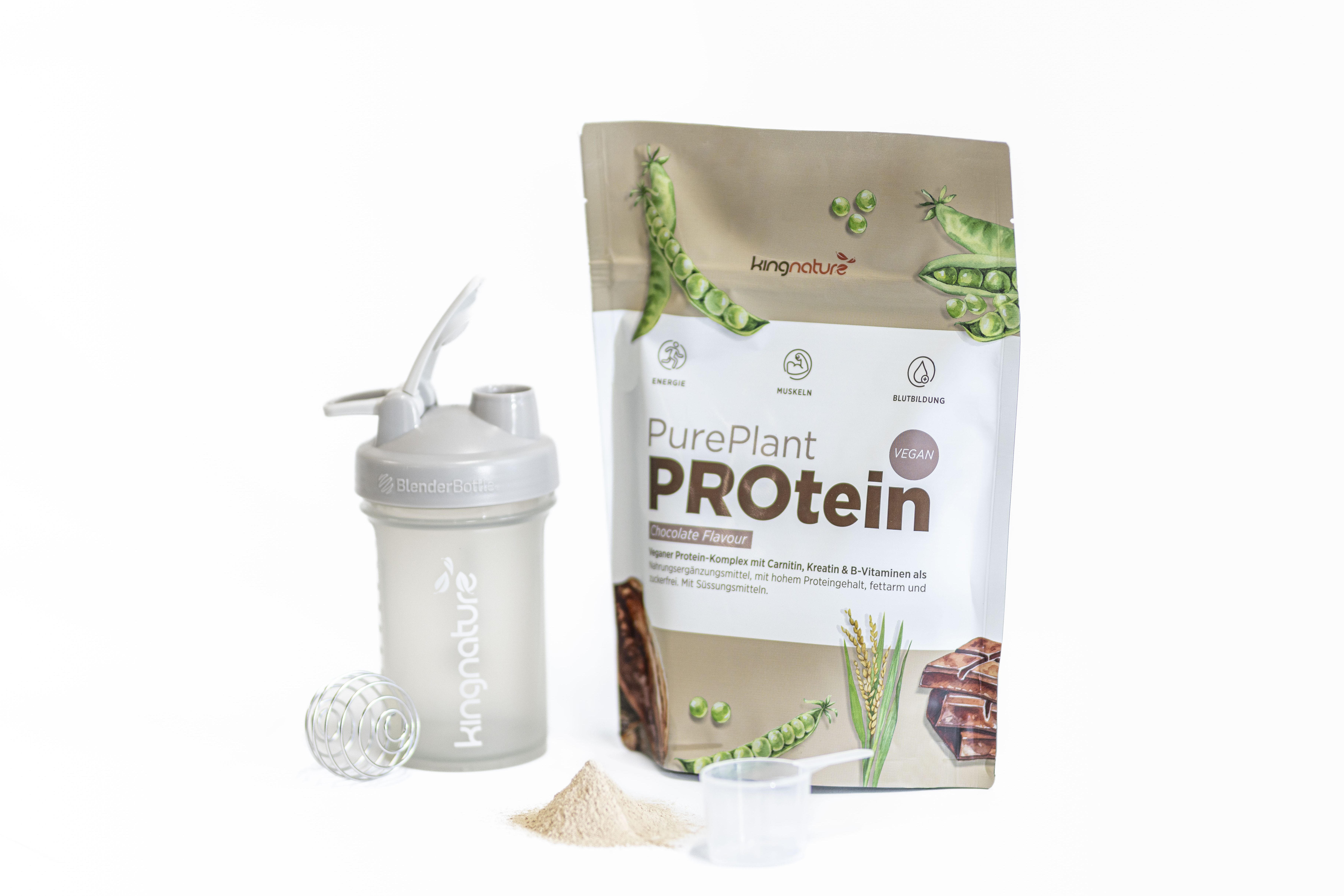 Ein Beutel Kingnature PurePlant Proteinpulver steht neben einer Shakerflasche, einer Metallmischkugel, einem Messlöffel und einem kleinen Haufen Proteinpulver, alles auf einem weißen Hintergrund.