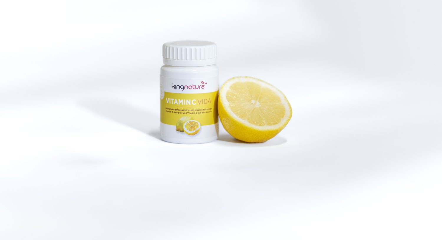 Offene Tablettenfläschchen mit roten Kapseln und Muscheln liegen verstreut auf einer Oberfläche. Ein rundes Etikett mit der Aufschrift „10 % im Mai“ weist auf einen 10%igen Rabatt auf Kingnature Nahrungsergänzungsmittel aus der Schweiz hin. Das Bild wirkt in einem sanften, werbenden Stil.