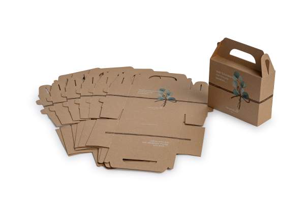 Neben mehreren flachen, braunen Geschenk-Box-Kartons mit Blattmotiv werden auch eine zusammengesetzte Schachtel mit Griff und einer ähnlichen Blattillustration sowie aufgedrucktem Text präsentiert.