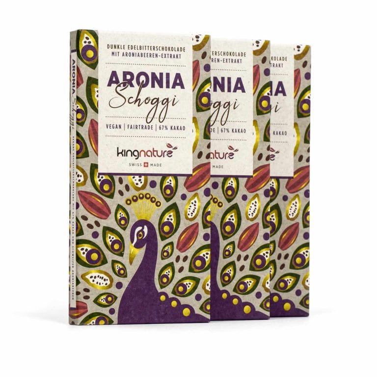 Vier Tafeln kingnature Aronia Schokolade stehen aufrecht und eignen sich dank ihrer farbenfrohen, gemusterten Verpackung mit Blatt- und Beerenmotiven perfekt als Geschenk. Die Etiketten betonen, dass die Schokolade vegan, fair gehandelt und mit 67 % Kakaoanteil ist.