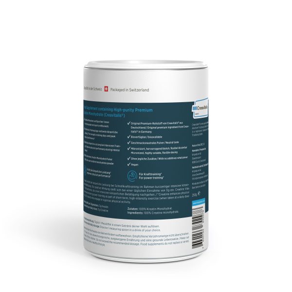 Ein zylindrischer Behälter mit einem weißen Deckel und einem blaugrünen Etikett, auf dem Produktinformationen und das Markenlogo eines Kreatin-Monohydrat-Nahrungsergänzungsmittels abgebildet sind. Der Text enthält Angaben zu den Inhaltsstoffen, eine Gebrauchsanweisung sowie Angaben zur Verpackung.