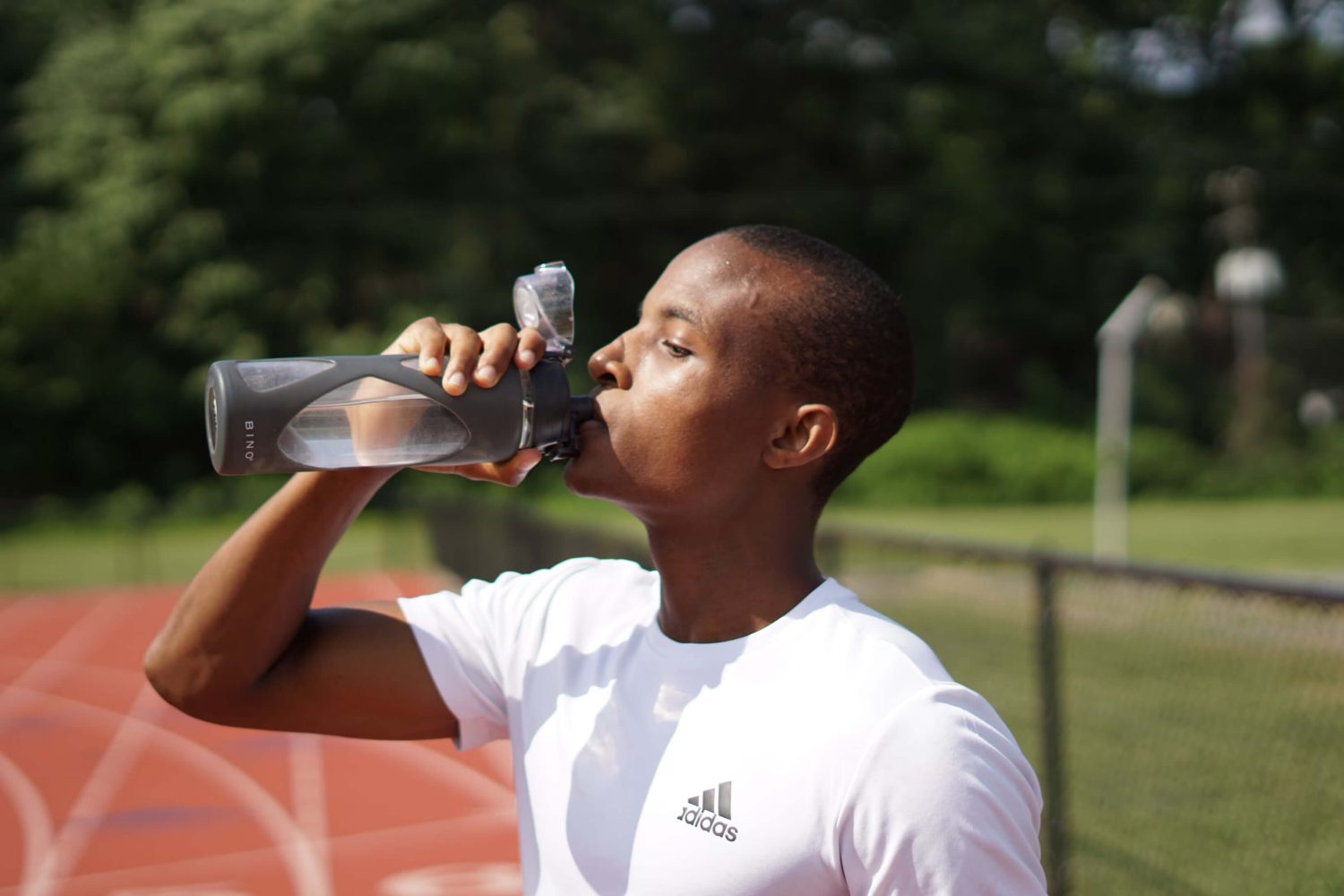 Ein Mann in Sportkleidung trinkt aus einer Wasserflasche.
