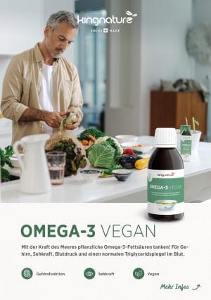 Ein Mann schneidet eine Gurke in einer hellen Küche. Frisches Gemüse liegt auf der Theke. Im Vordergrund hängt ein Produkte-Flyer (ohne Muster) neben einer Omega-3-Vegan-Flasche, die für ein pflanzliches Nahrungsergänzungsmittel wirbt.