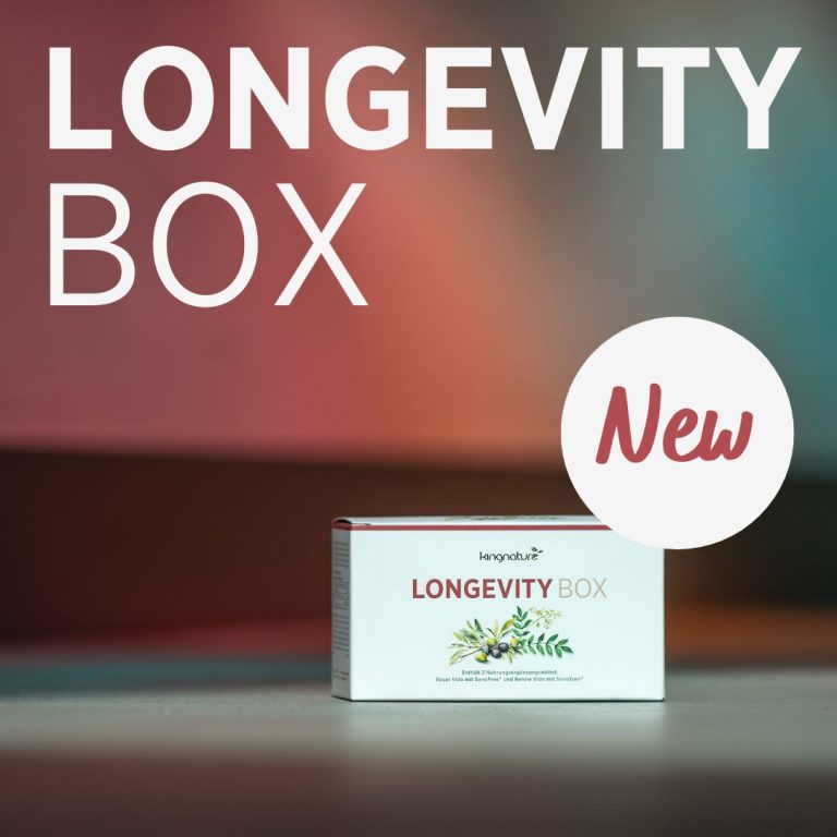 Ein Longevity Box-Produkt liegt auf einer glatten Oberfläche mit unscharfem Hintergrund. Darüber steht in großem weißen Text „LONGEVITY BOX“, und neben dem Produkt befindet sich ein rundes „Neu“-Etikett mit der Aufschrift „Reset Vida“ oder „Renew Vida“.
