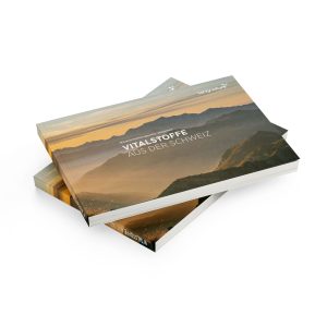 Zwei übereinanderliegende Broschüren – die Produktbroschüre „kingnature“ mit einem Titelbild, das Berge bei Sonnenuntergang zeigt, und dem deutschen Titel „VITALSTOFFE AUS DER SCHWEIZ“ in weißer Schrift.