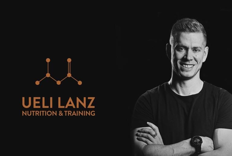 Ein Mann mit kurzen Haaren und einem schwarzen T-Shirt lächelt mit verschränkten Armen und steht neben dem Logo von Lanz Nutrition mit verbundenen Punkten und dem Text UELI LANZ NUTRITION & TRAINING auf schwarzem Hintergrund.