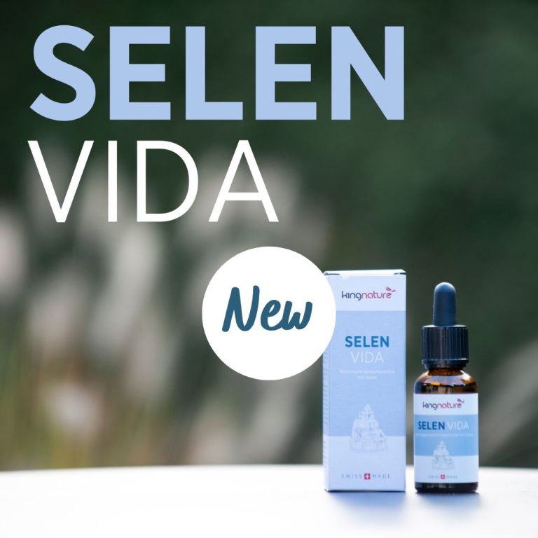 Eine Flasche und eine Schachtel Selen Vida Natriumselenit Tropfen mit einer Pipette stehen im Freien. Der große Text darüber lautet „SELEN VIDA“ und „Neu“ in einem weißen Kreis. Der Hintergrund ist mit sanft verschwommenem Grün gestaltet.