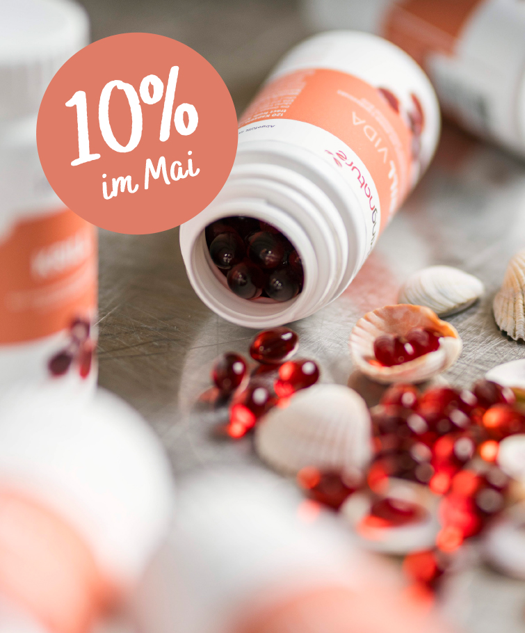 Offene Tablettenfläschchen mit roten Kapseln und Muscheln liegen verstreut auf einer Oberfläche. Ein rundes Etikett mit der Aufschrift „10 % im Mai“ weist auf einen 10%igen Rabatt auf Kingnature Nahrungsergänzungsmittel aus der Schweiz hin. Das Bild wirkt in einem sanften, werbenden Stil.