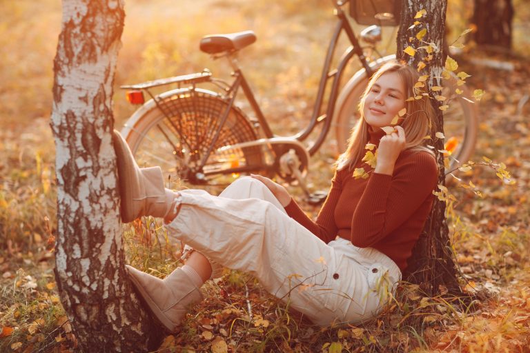 Eine Frau sitzt neben ihrem Fahrrad zwischen zwei Bäumen in der Natur