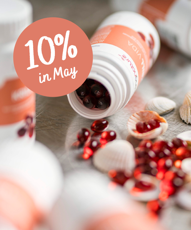 Eine Flasche Kingnature Red-Kapseln liegt umgekippt auf einem Tisch. Muscheln und weitere Kapseln liegen verstreut herum. Eine Grafik zeigt „10 % im Mai“, während andere ähnliche Flaschen im Hintergrund unscharf sind.
