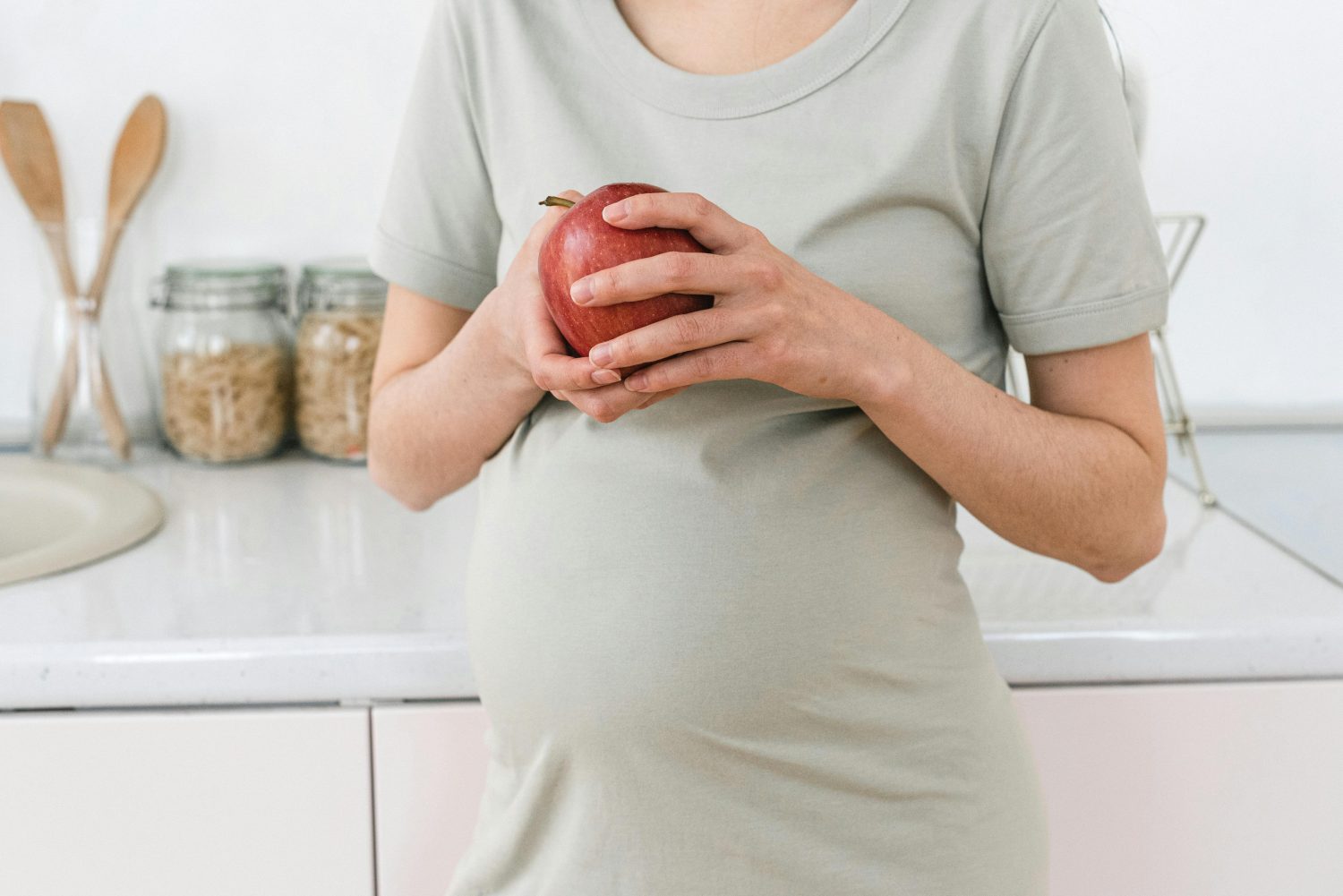 Schwangere Frau isst Apfel, um Vitamine zu sich zu nehmen
